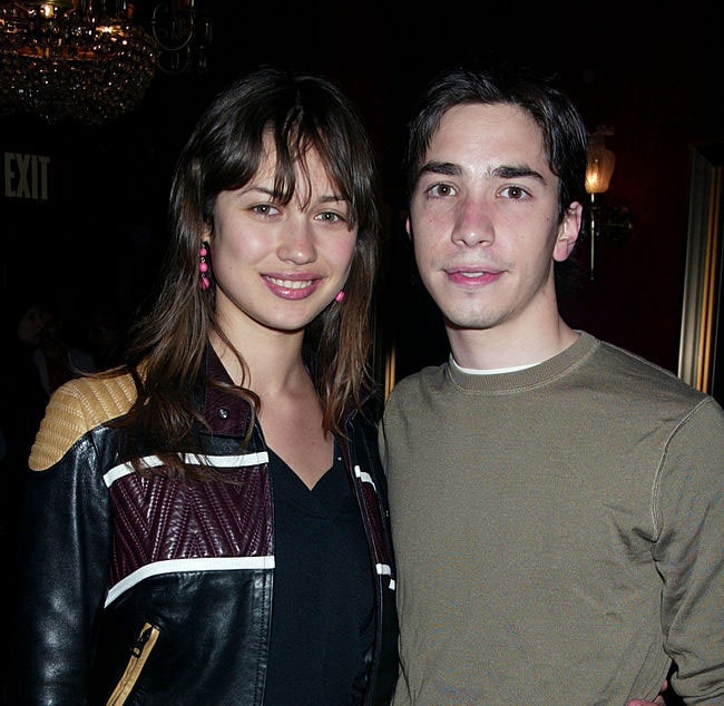 Justin Long and Olga Kurylenko taking a photo together.
